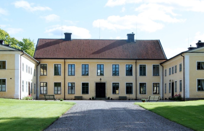 En gul byggnad vid en gräsmatta med en grusgång.