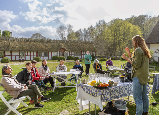 En grupp människor lyssnar på en föreläsning utomhus.