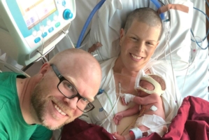 En kvinna med sin nyfödda bebis på sjukhuset och hennes man bredvid.