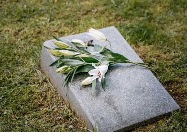 En bukett med vita blommor ligger på en gravsten.