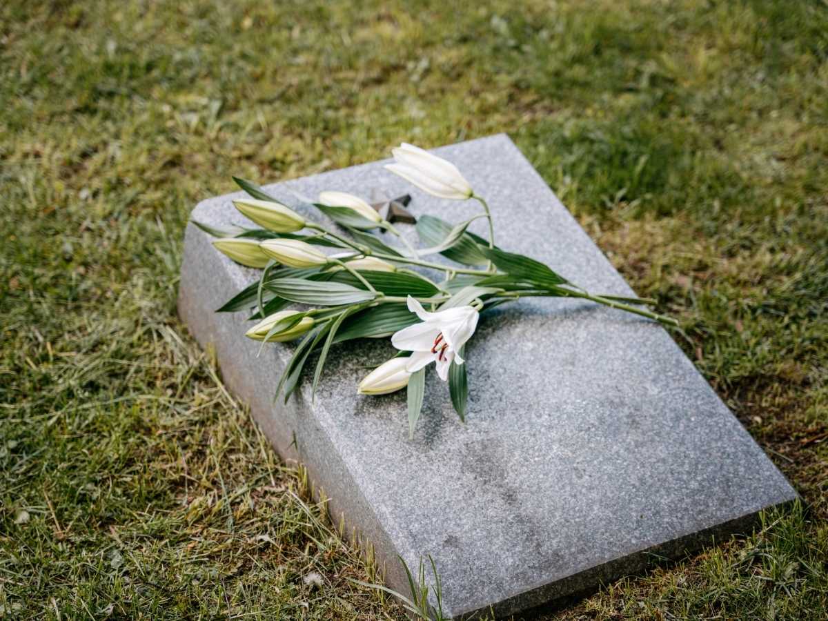 En bukett med vita blommor ligger på en gravsten.