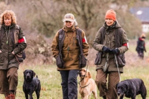 Tre kvinnor med varsin hund är ute och går i naturen.