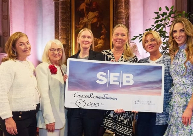 En grupp kvinnor står på rad och håller upp en SEB-check.