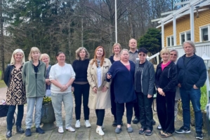 En grupp människor står på rad utomhus och ler mot kameran.