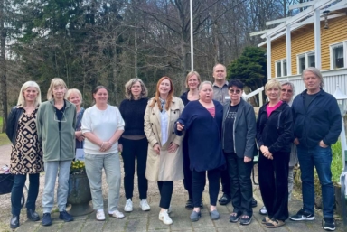 En grupp människor står på rad utomhus och ler mot kameran.