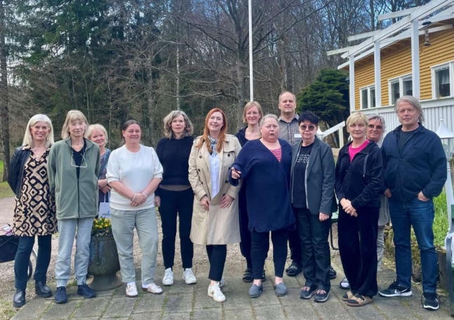 En grupp människor står på rad utomhus och ler mot kameran.