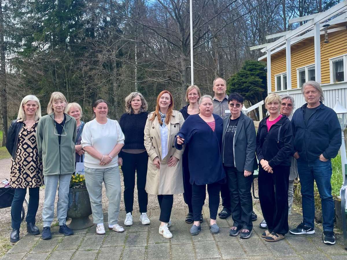 En grupp människor står på rad utomhus och ler mot kameran.