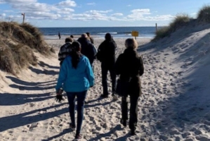 En grupp människor går vid en strand.