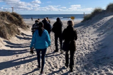 En grupp människor går vid en strand.