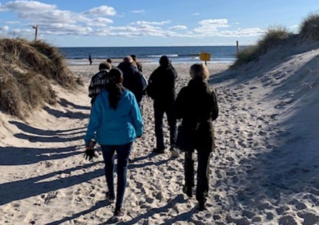 En grupp människor går vid en strand.