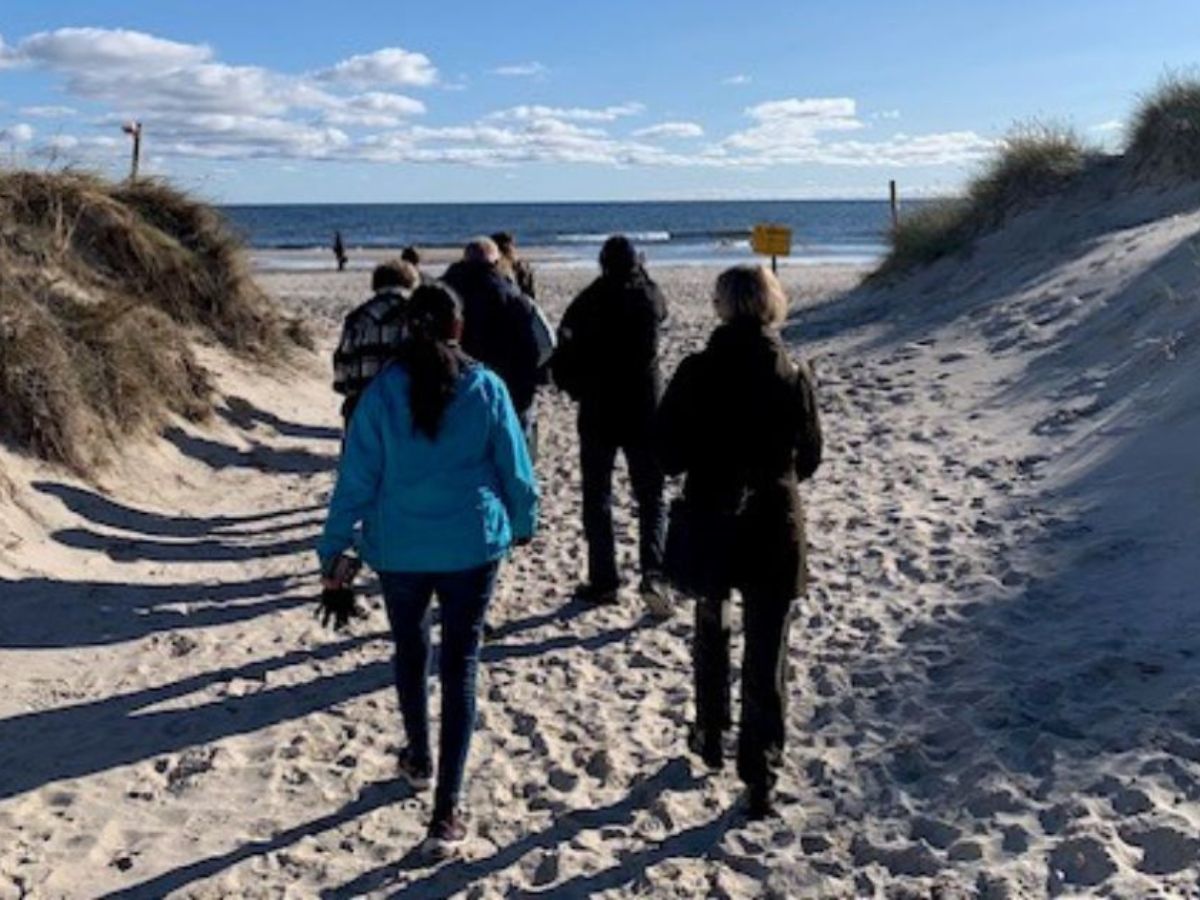 En grupp människor går vid en strand.
