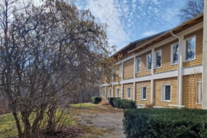 Lydiagården från utsidan, en gul träbyggnad med natur runt omkring.