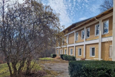 Lydiagården från utsidan, en gul träbyggnad med natur runt omkring.