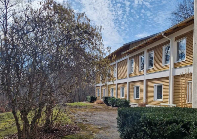 Lydiagården från utsidan, en gul träbyggnad med natur runt omkring.