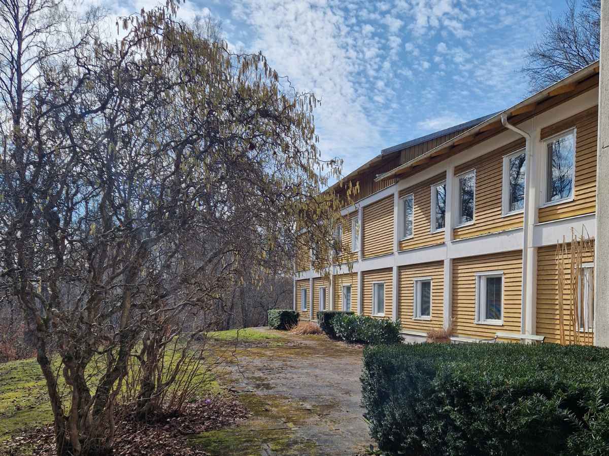 Lydiagården från utsidan, en gul träbyggnad med natur runt omkring.