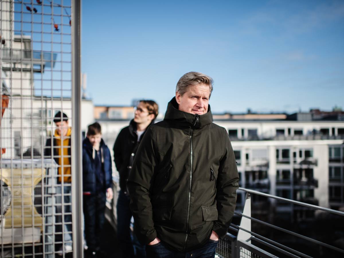 En man står på sin balkong med sina tre söner i bakgrunden.