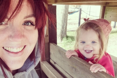 En kvinna och hennes dotter leker på en lekplats.