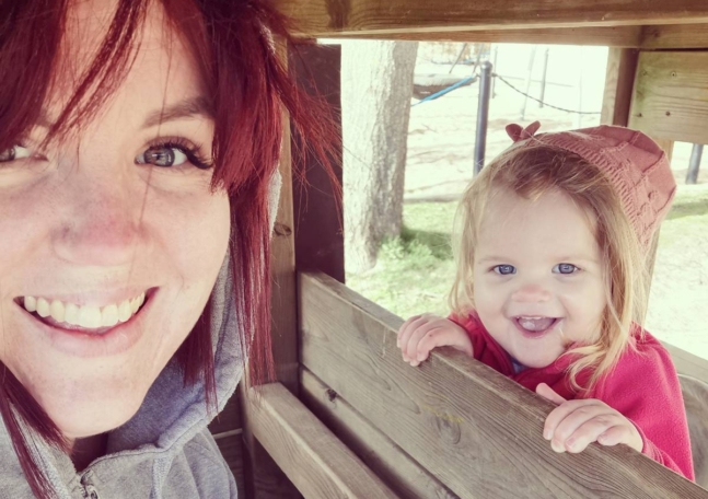 En kvinna och hennes dotter leker på en lekplats.