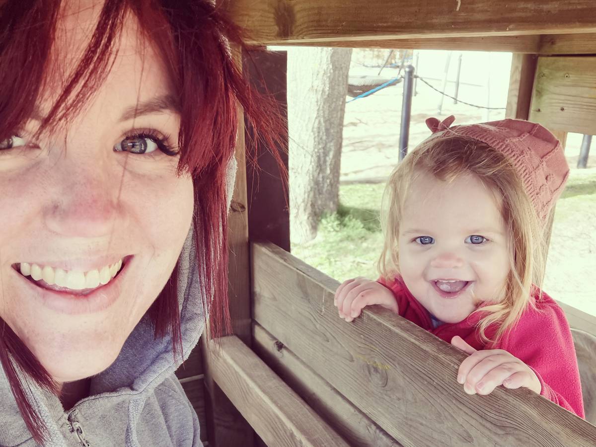 En kvinna och hennes dotter leker på en lekplats.