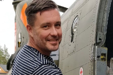 En man i randig tröja ler och tittar in i kameran.