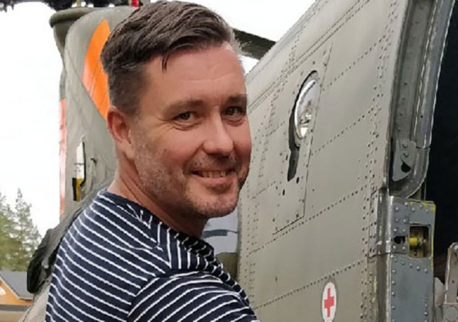 En man i randig tröja ler och tittar in i kameran.