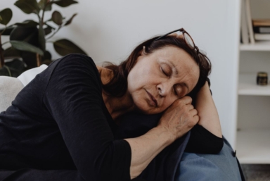 En kvinna blundar och vilar i en soffa.