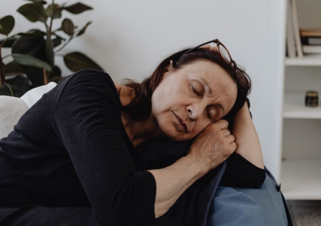 En kvinna blundar och vilar i en soffa.