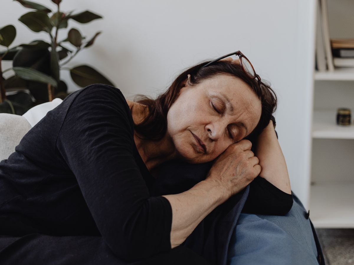 En kvinna blundar och vilar i en soffa.