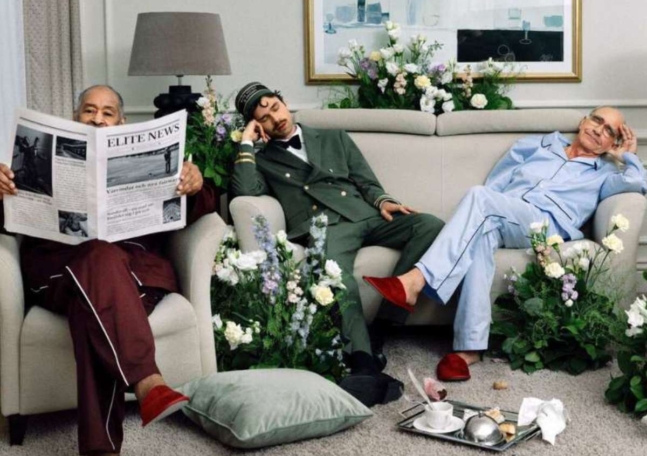 Tre personer sitter i en soffa och fåtölj i ett fint hotellrum.